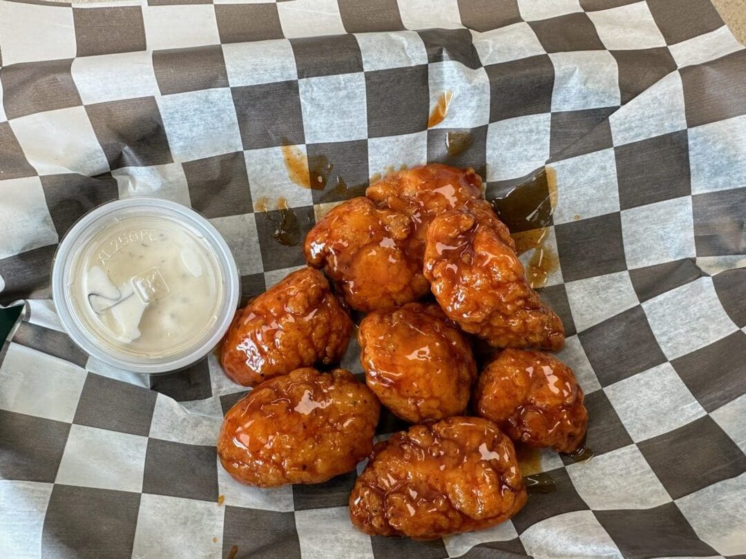 A basket of chicken wings with dipping sauce.