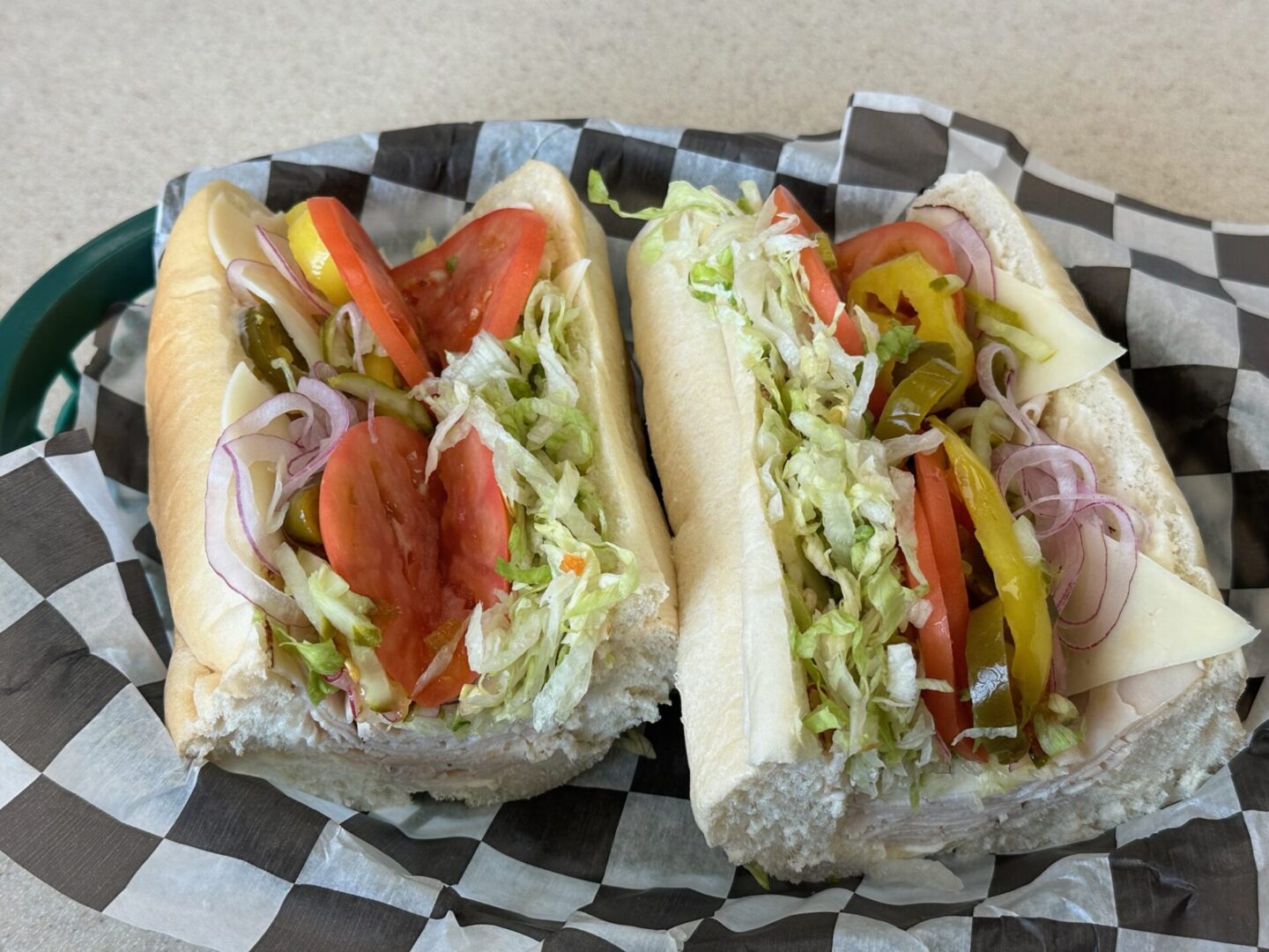 Two hot dogs with toppings on a checkered paper.