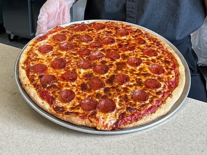 A pepperoni pizza is on the table ready to be eaten.